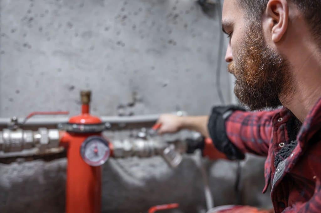 The-man-looks-at-the-faucet-pipes-valve-pressure-meter